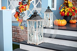 Cozy porch of the house with wooden lanterns in fall time. Halloween design home with yellow fall leaves and lamps.