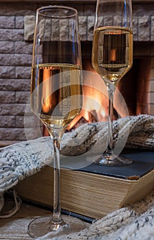 Cozy scene before fireplace with glass of wine, book and wool warm scarf