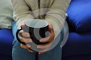 Cozy scene. Young woman with cup of coffee in hands.