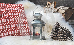 Cozy sitting area on wooden veranda with lambskin, lantern and red and white pillows