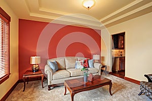 Cozy sitting room with antique beige sofa and red wall behind.