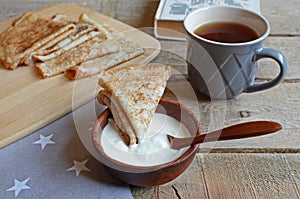 Cozy snack with Russian style pancakes and book during Maslenitsa Old wooden background