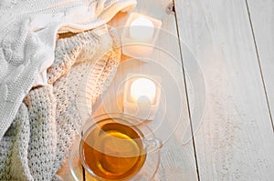 Cozy and soft winter background. Warm sweaters or blankets, candles, cup of tea.