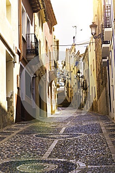 The cozy street of the old European city of Relleu is paved with cobblestones in the form of a picture. Mediterranean architecture