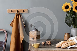 Cozy and stylish composition of creative dining room with copy space, wooden console, sunflowers and personal accessories.