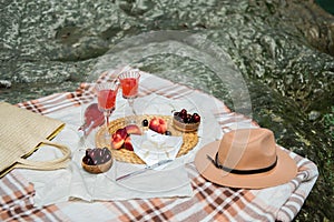 Cozy summer picnic near the lake with wine, cherry, peaches, brie cheese, camamber. Romantic picnic for Valentine& x27;s