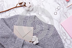 Cozy sweater with envelope , pink notebook and rings on marble background