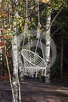 A cozy swing near a wooden country house on a sunny autumn day. Camping. Vertical