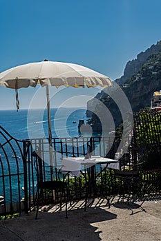 A cozy table in a cafe with a white tablecloth with a beautiful view of the city of Positano in Italy