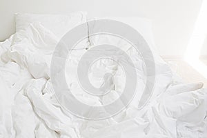 Cozy white bed in the morning. White sheets and pillow on bed in modern white room. Lazy days. Stay home. Comfortable place. Relax