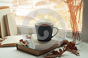 Cozy window with autumn leaves, a book, a mug of tea, time to read, autumn weekend concept.