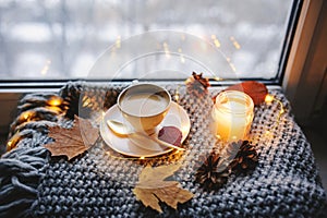 Cozy winter or autumn morning at home. Hot coffee with gold metallic spoon, warm blanket, garland and candle lights