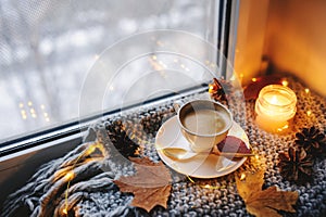 Cozy winter or autumn morning at home. Hot coffee with gold metallic spoon, warm blanket, garland and candle lights