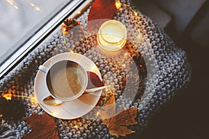 Cozy winter or autumn morning at home. Hot coffee with gold metallic spoon, warm blanket, garland and candle lights photo