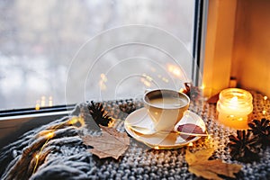 Cozy winter or autumn morning at home. Hot coffee with gold metallic spoon, warm blanket, garland and candle lights