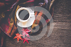 Cozy winter background, cup of hot coffee with marshmallow and leaves maple on season autumn, warm knitted sweater on old wooden b