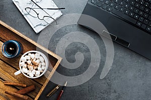 Cozy winter business flatlay arrangement with black laptop, wooden tray with vegan cocoa