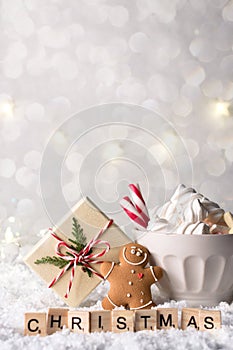 Cozy winter composition with a cup of hot chocolate with marshmallows gingerbread man cookies and gift on a light festive backgrou