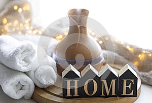 Cozy winter composition with essential oil aroma diffuser and wooden word Home.