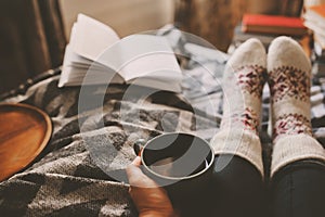 cozy winter day at home with cup of hot tea, book and warm socks