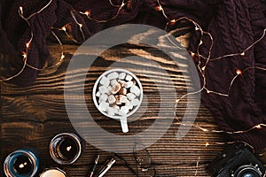 Cozy winter flatlay arrangement with Christmas lights, vegan cocoa, glasses, knitted sweater and candles