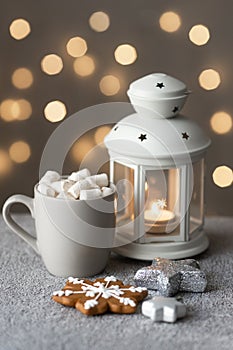 Cozy winter holiday background with gingerbread cookies on table, candles and a cup of coffee with marshmallows