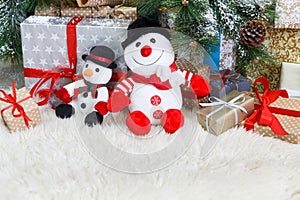 Cozy christmas background. Toy snowmen and presents under new year tree