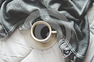 Cozy winter home background, cup of hot coffee with marshmallow, warm knitted sweater on white bed background, vintage tone. photo