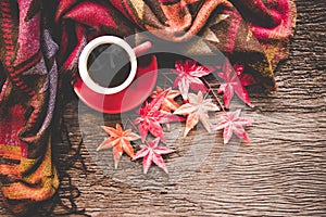 Cozy winter maple background, red cup of hot coffee with marshmallow, warm knitted sweater on old wooden background,