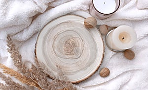 Cozy winter mockup still life scene with wooden round tray, candles and walnuts on white plaid. Nordic home decor flat lay