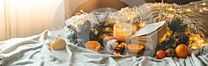 Book and Tangerines in a winter composition, Christmas trees, candles, cones, cotton, cinnamon. Symbol of New Year and Christmas