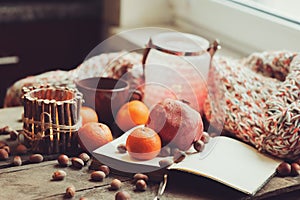 Cozy winter morning at home with fruits, nuts and candles, selective focus