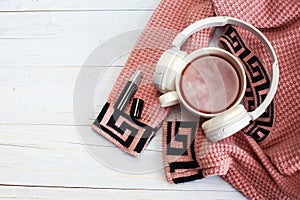 Cozy winter morning .Hot tea or coffee, knitted sweater, perfume and headphones on wooden background .