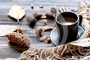 Cozy winter relax time.  Cup of hot coffee  with blanket, autumn leaves, cinnamon sticks item brown on the old wood background in