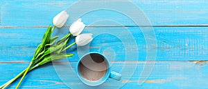 Cozy winter relax time.  Cup of hot coffee with tulip flower on the blue wood background