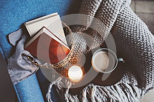 Cozy winter weekend at home. Morning with coffee or cocoa, books, warm knitted blanket and nordic style chair. Hygge concept.