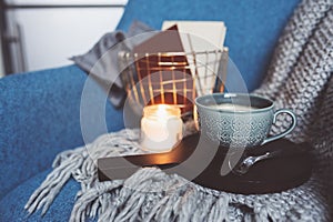 Cozy winter weekend at home. Morning with coffee or cocoa, books, warm knitted blanket and nordic style chair. Hygge concept.