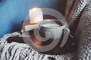 Cozy winter weekend at home. Morning with coffee or cocoa, books, warm knitted blanket and nordic style chair. Hygge concept.