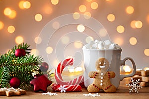 Cozy wintertime scene. Gingerbread man, cup of hot cocoa with marshmallow and Christmas fir branch