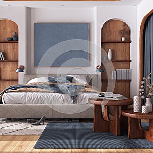 Cozy wooden bedroom with parquet, double bed with duvet, tables and carpet in white and blue tones. Niches and arched door.