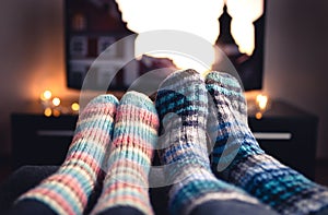 Cozy woolen socks. Couple watching tv in winter. Man and woman using online streaming service for movies and series.