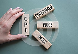 CPI - Consumer Price Index symbol. Concept word CPI on wooden blocks. Businessman hand. Beautiful grey green background. Business