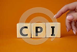 CPI - Consumer Price Index symbol. Concept word CPI on wooden cubes. Businessman hand. Beautiful orange background. Business and