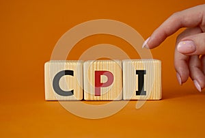 CPI - Consumer Price Index symbol. Concept word CPI on wooden cubes. Businessman hand. Beautiful orange background. Business and