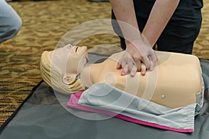 CPR First Aid Training with CPR dummy in the class. Demonstrating chest compressions concept