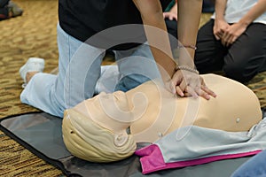 CPR First Aid Training with CPR dummy in the class. Demonstrating chest compressions concept