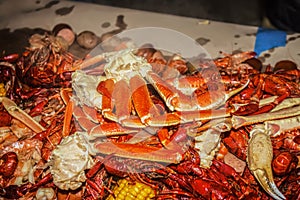 Crab claws and crawdads and shrimp piled on a paper covered cable with ears of corn and onions at a seafood boil - shallow focus