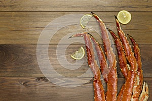 Crab claws with lemon on wooden background