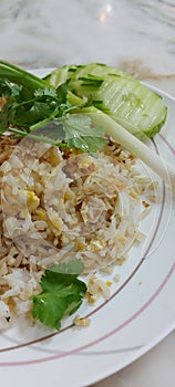 Crab meat fried rice with slice cucumber and spring onion in white plate