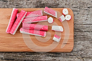 Crab sticks on cutting board on rustic wooden table